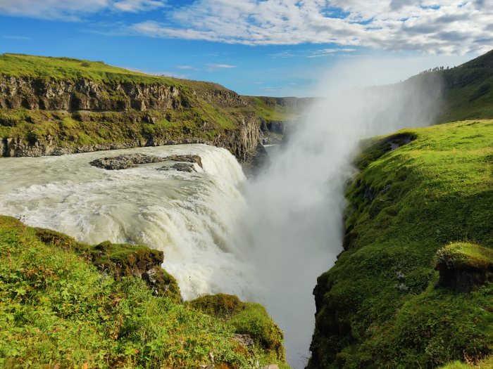Acqua che cade da un dirupo fra colline verdi e rocce