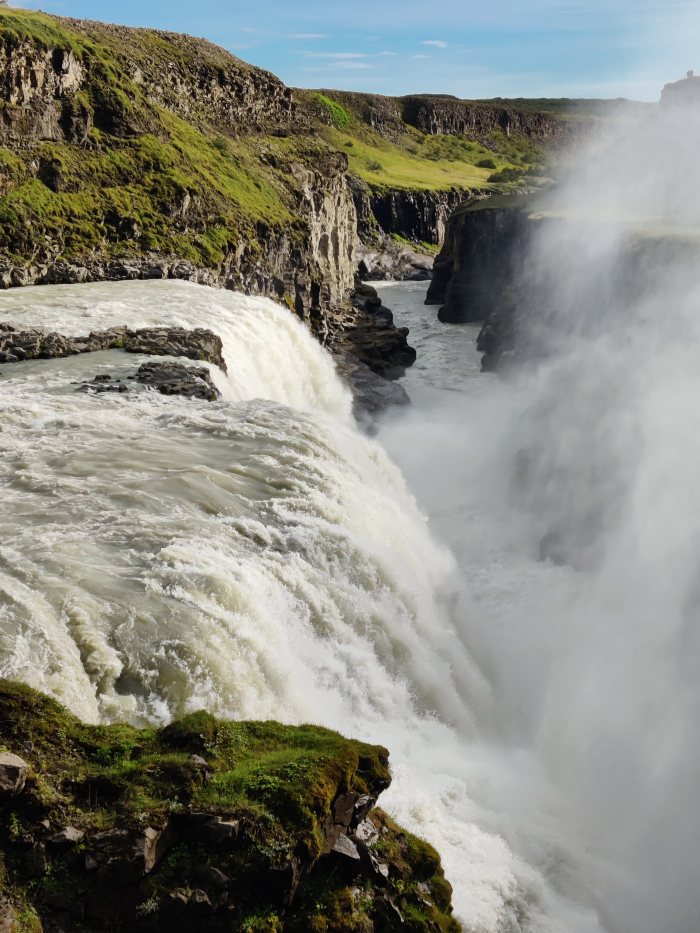 Acqua che cade da un dirupo roccioso con vegetazione verde intorno