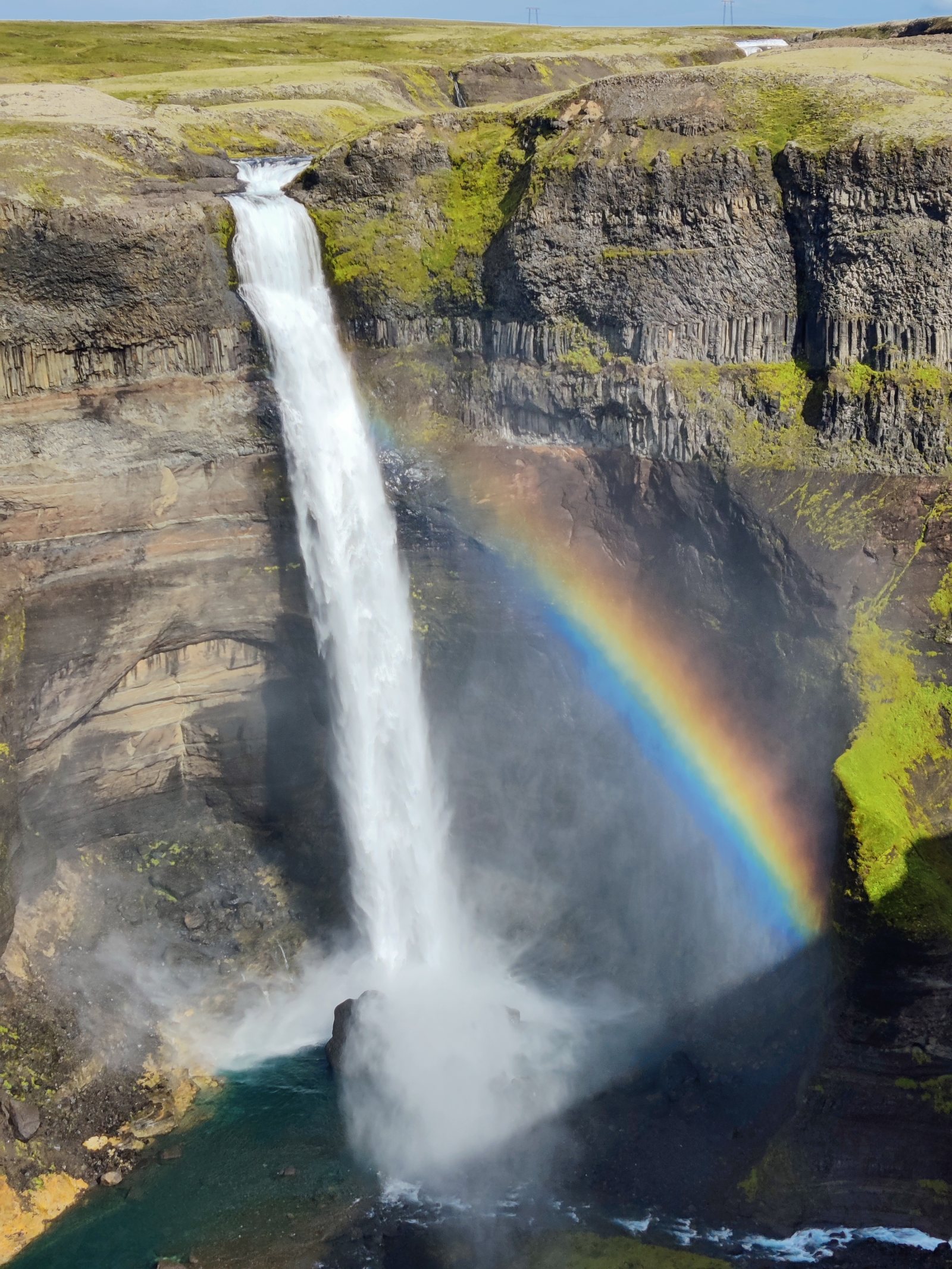 Cascata che precipita in un canyon con arcobaleno