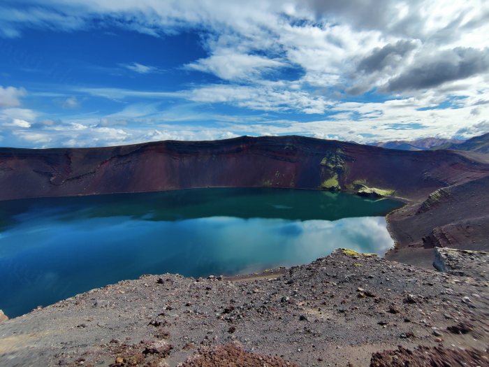 Lago dentro un cratere vulcanico con bordi rossi e acqua blu