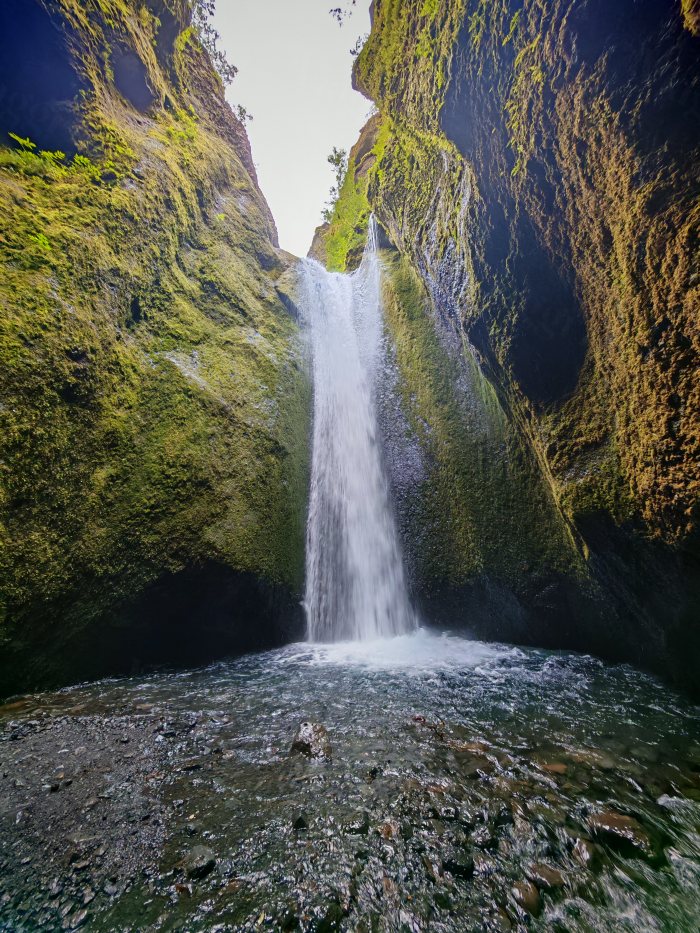 Acqua che cade in un canyon fra pareti coperte di muschio
