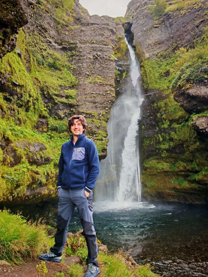 Una persona in posa davanti a una cascata in un canyon di muschio