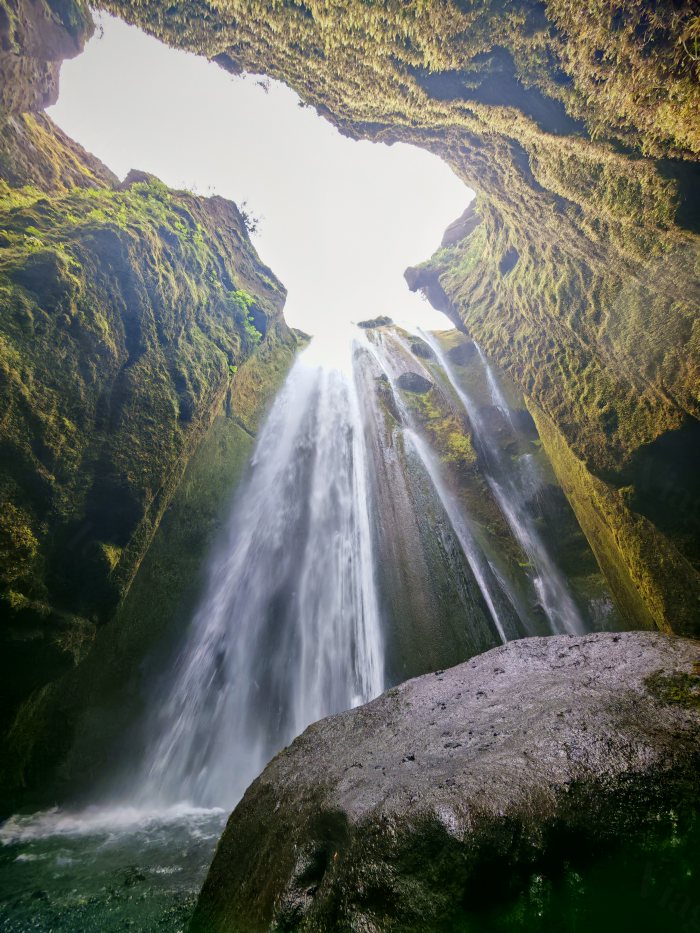 Vista dal basso dell'acqua che cade davanti a una grotta rocciosa