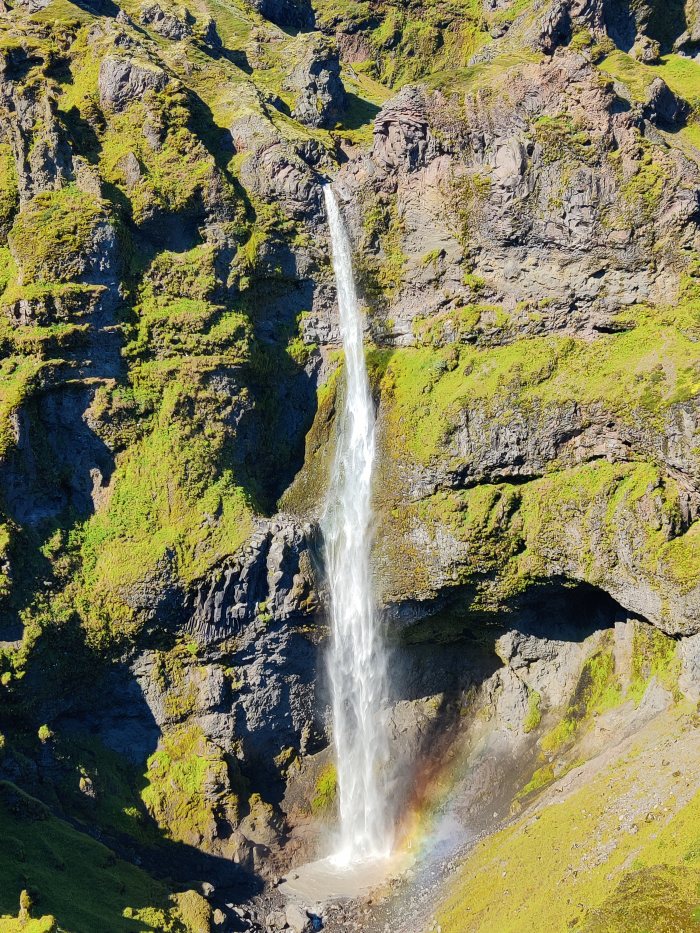 Salto d'acqua che cade su rocce ricoperte di vegetazione verde