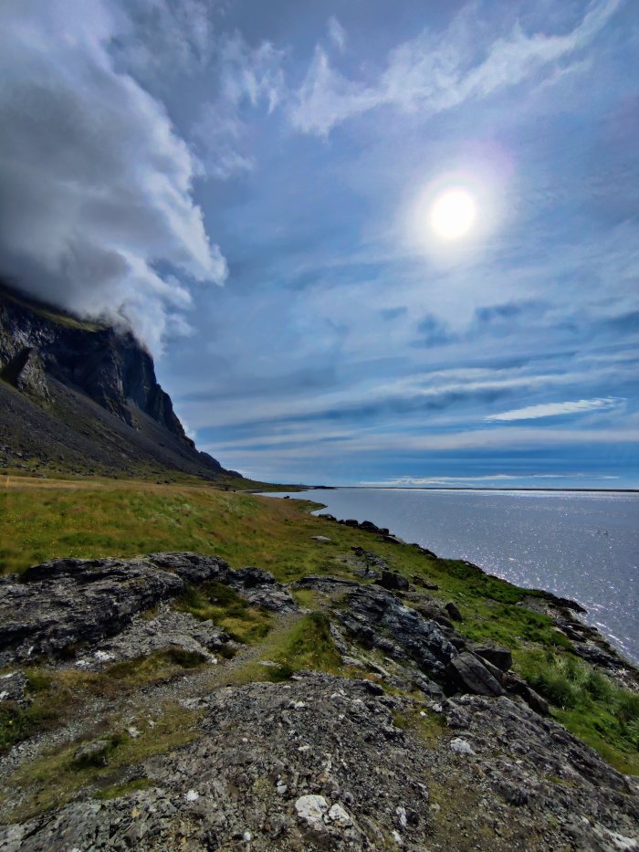 Paesaggio costiero con montagna e mare sotto il sole