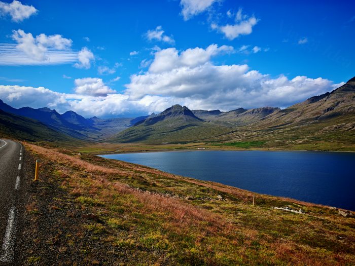 Strada asfaltata fiancheggiata da un lago e montagne