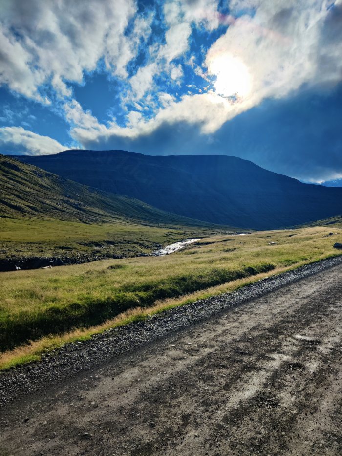 Strada sterrata con fiume e montagna in lontananza