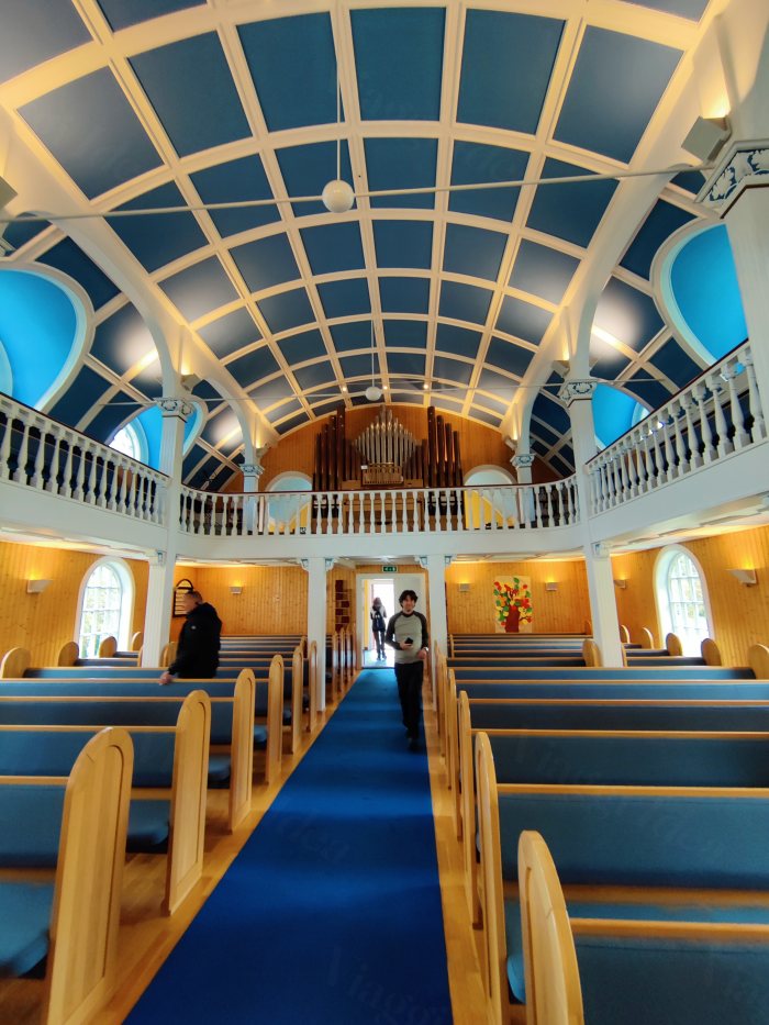 Uomo e donna camminano nel corridoio di una chiesa con banchi e organo