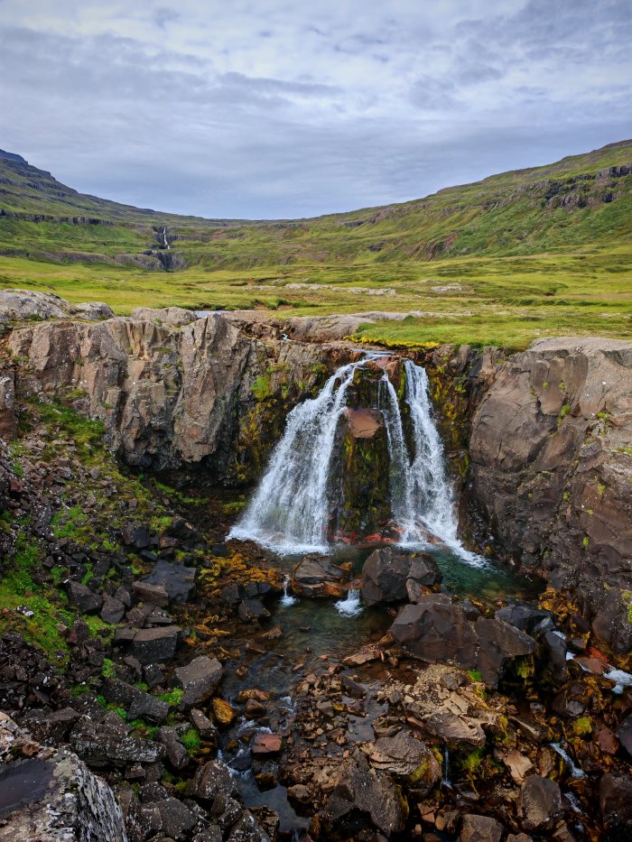 Cascata che cade su rocce in un paesaggio montuoso