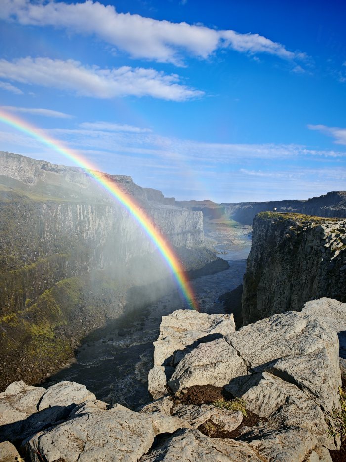 Arcobaleno che attraversa un canyon con fiume e rocce