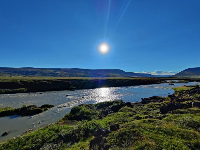 Fiume che scorre fra colline sotto il sole