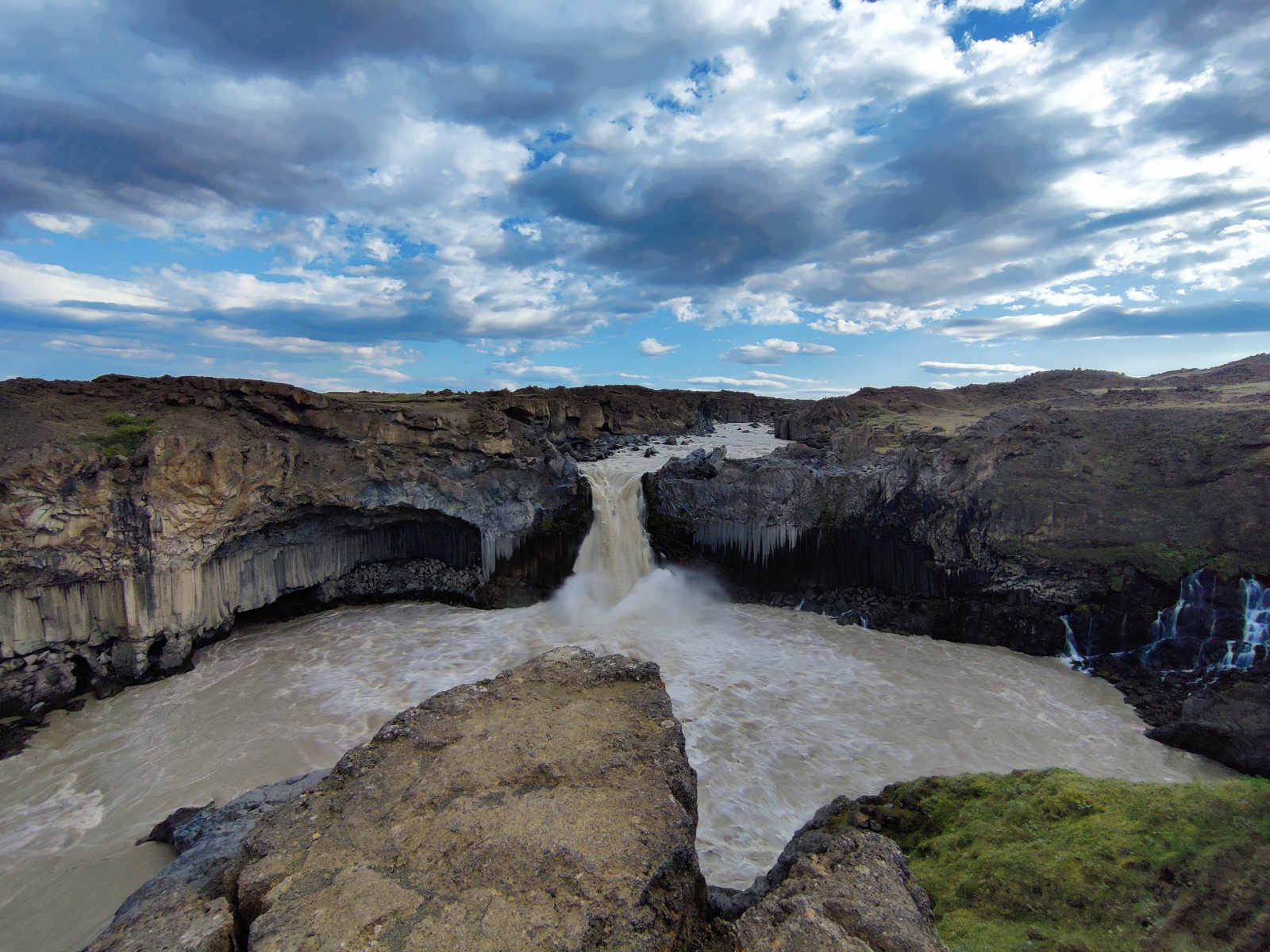 Acqua che cade da un dirupo roccioso in un canyon con colonne basaltiche