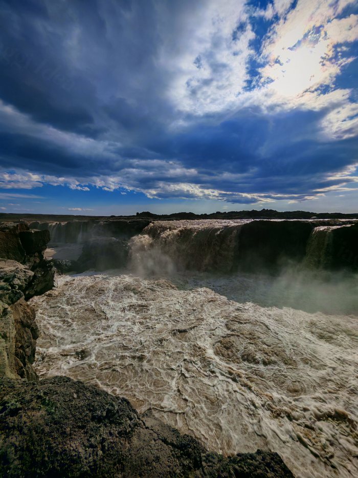 Acqua che cade da un precipizio fra rocce e nuvole