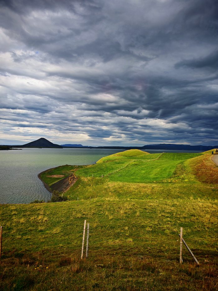 Paesaggio con colline verdi, lago e cielo nuvoloso