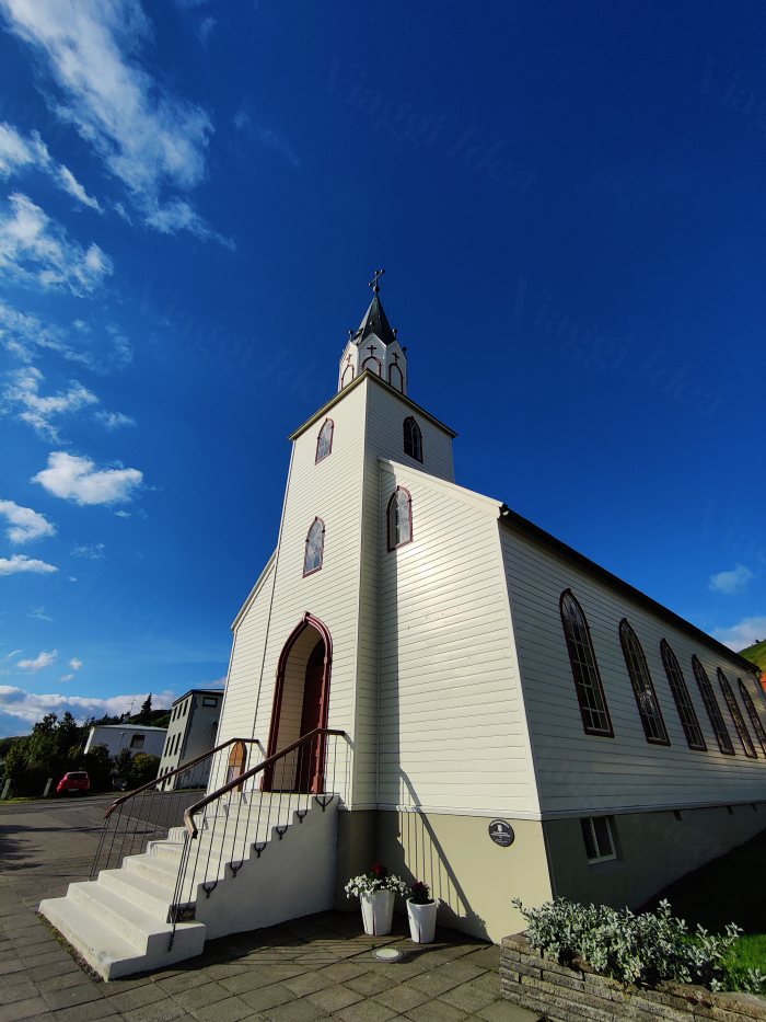Chiesa bianca con campanile e scalini esterni sotto cielo blu