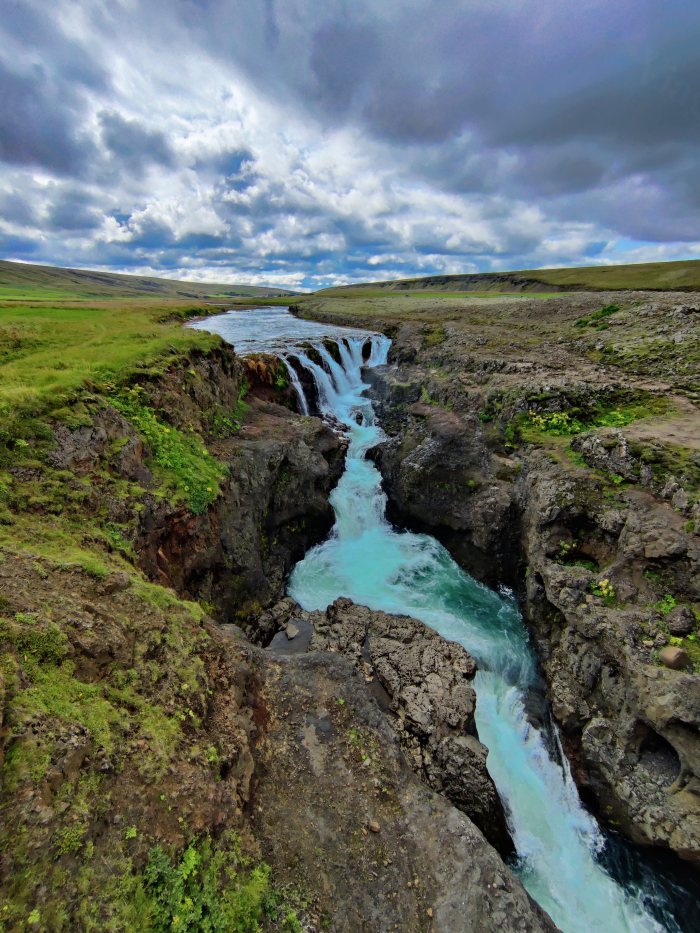 Acqua che scorre in un canyon roccioso fra colline verdi