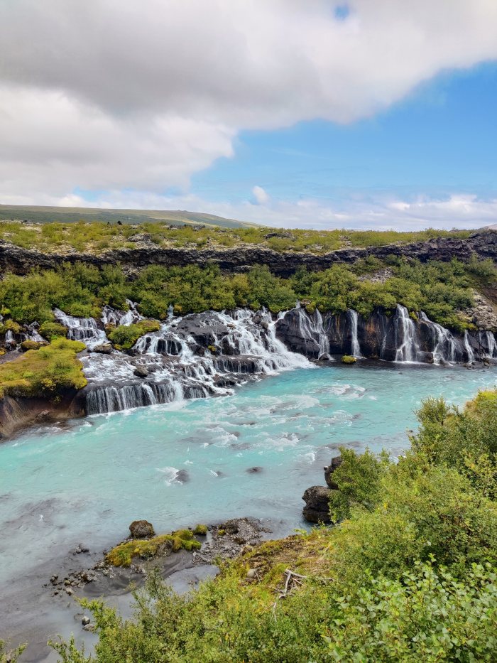 Acqua che scorre da rocce su un letto di fiume turchese