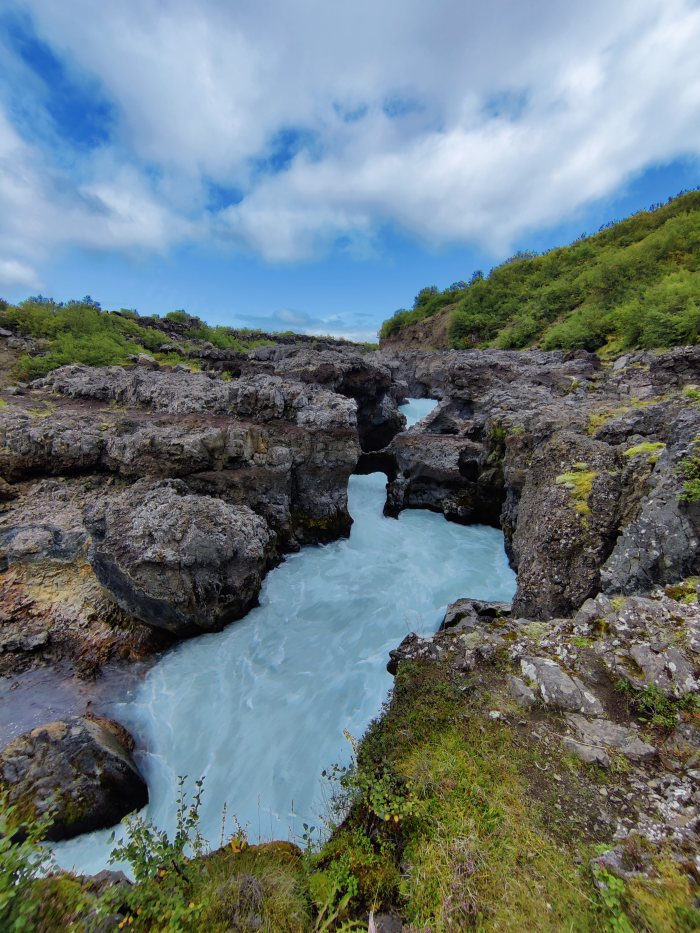 Fiume che scorre fra rocce e vegetazione in un canyon naturale