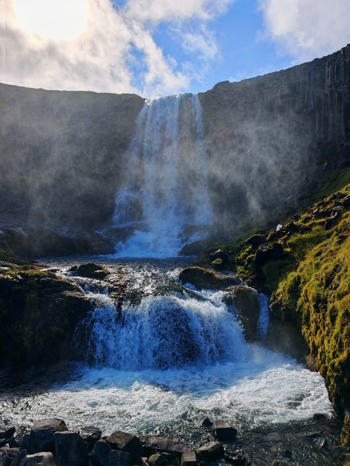 Cascata che cade su rocce creando spruzzi e nebbia