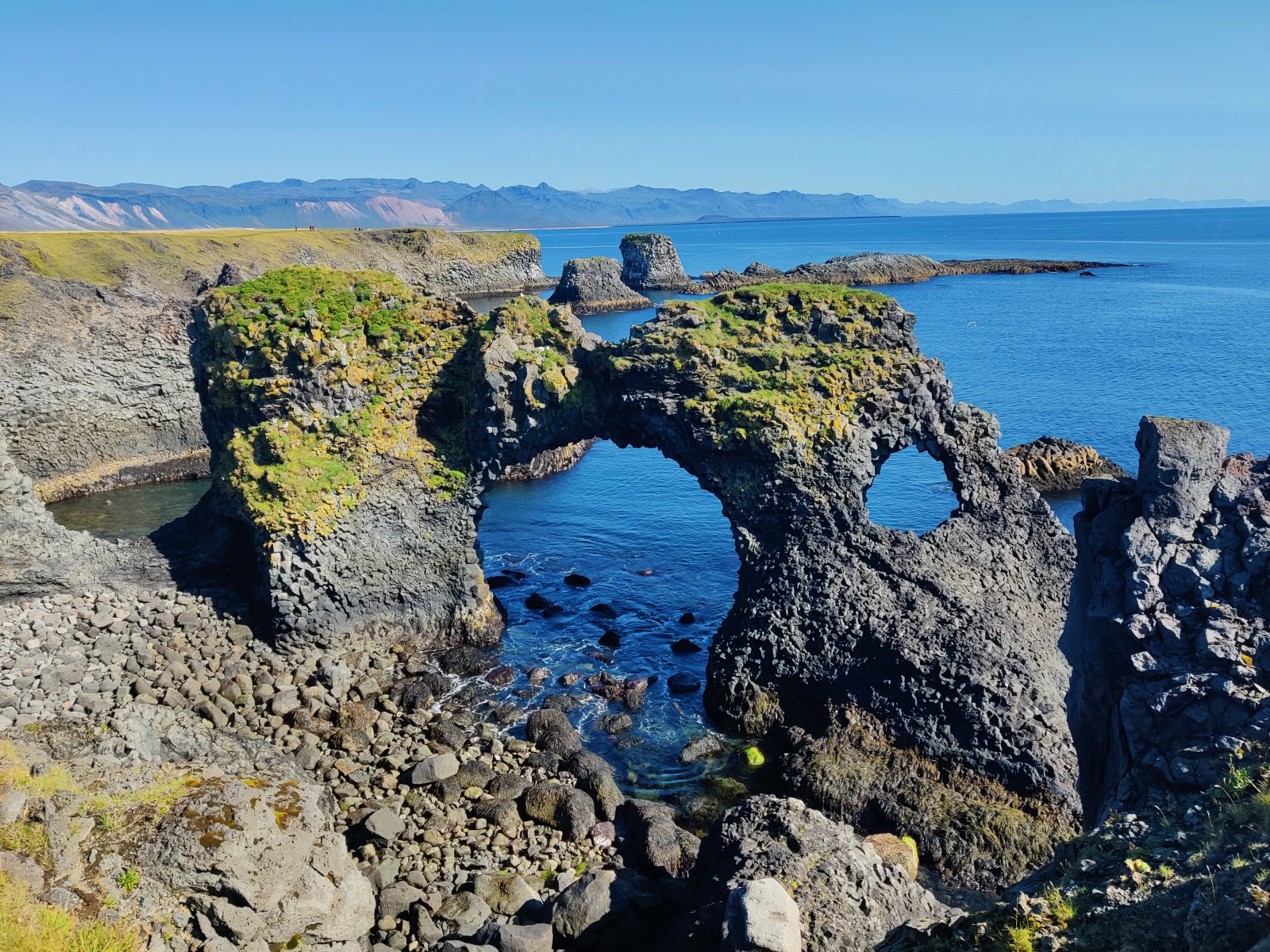 Arco roccioso naturale con mare e colline sullo sfondo