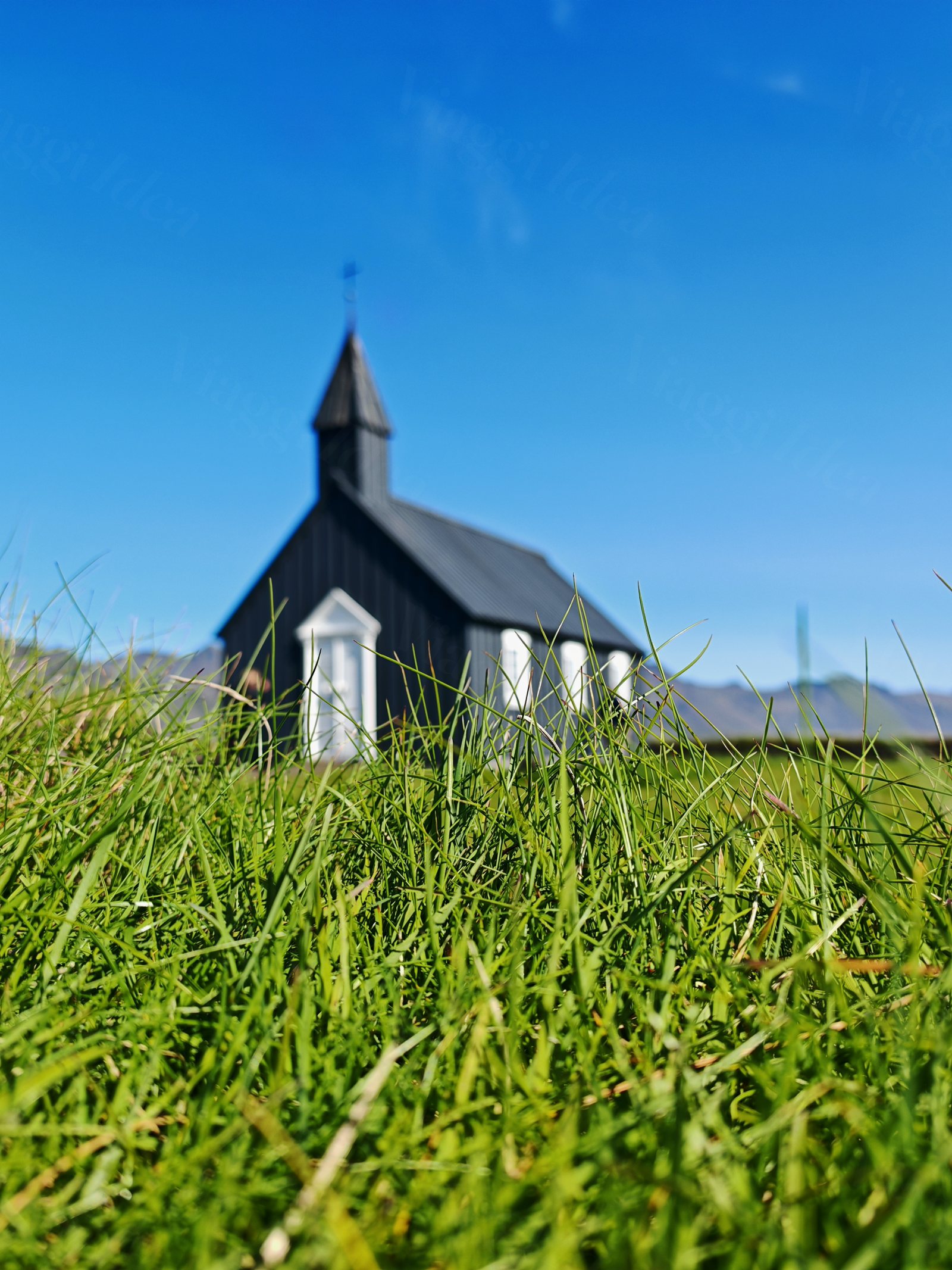 Chiesa nera con dettagli bianchi in un campo di erba verde