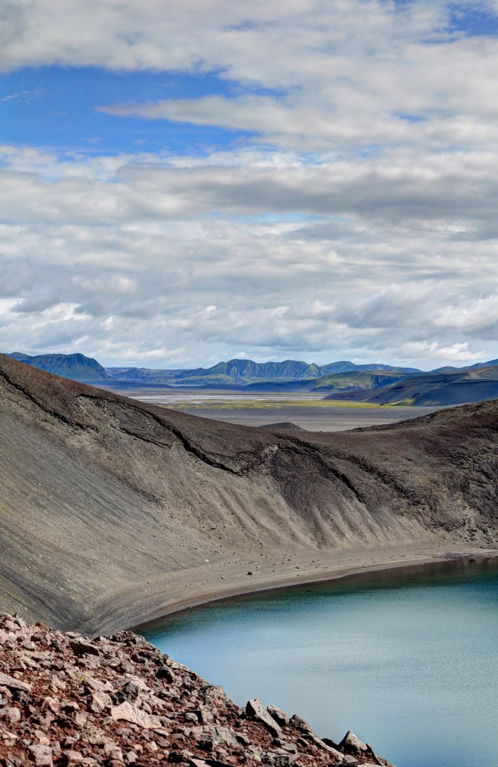 Paesaggio vulcanico con lago e montagne in lontananza