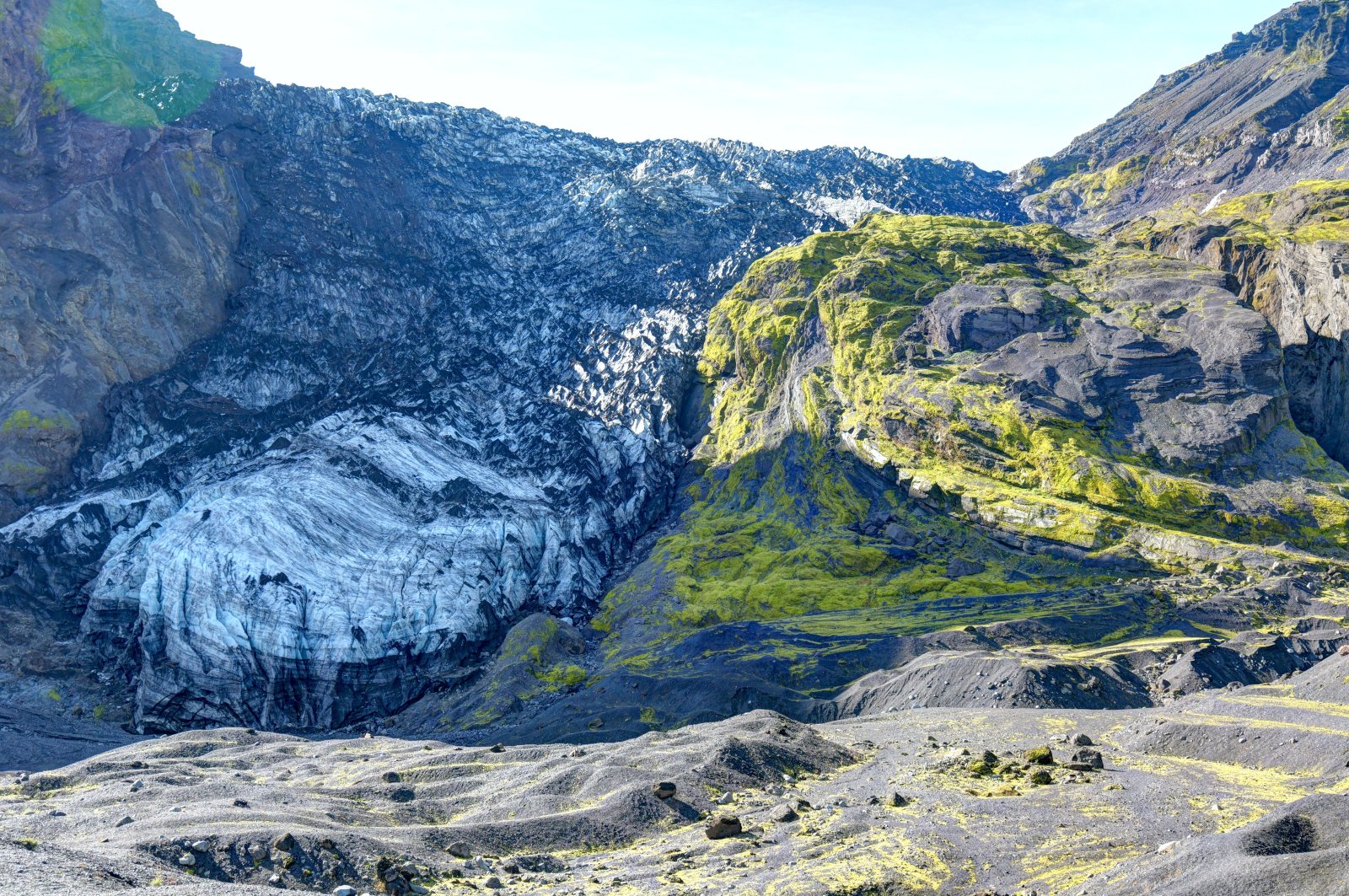 Rocce e colate di lava coperte di muschio con ghiaccio sullo sfondo