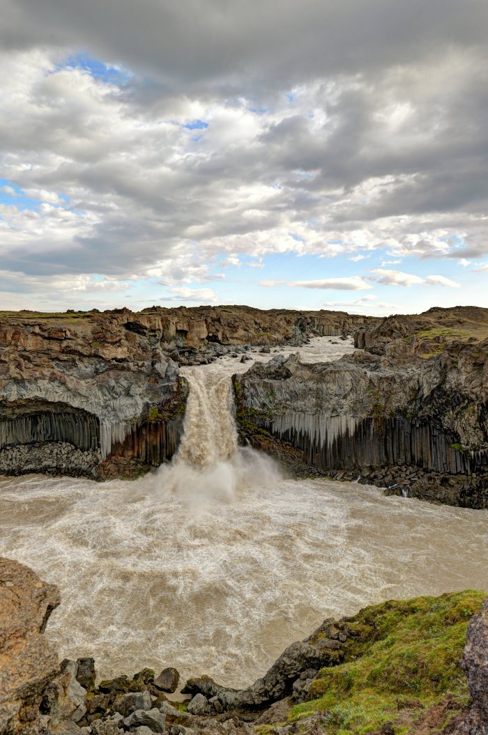 Acqua che cade da un dirupo fra colonne basaltiche in un paesaggio selvaggio