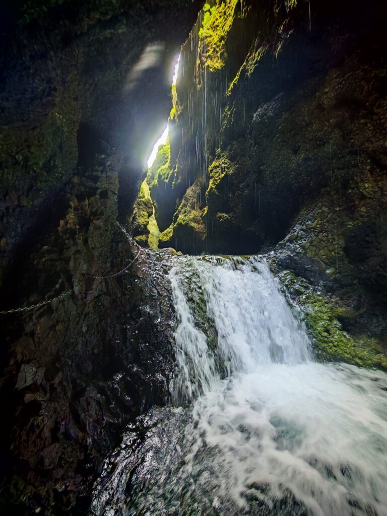 Piccola cascata incassata tra pareti scure, con luce che arriva dall'alto