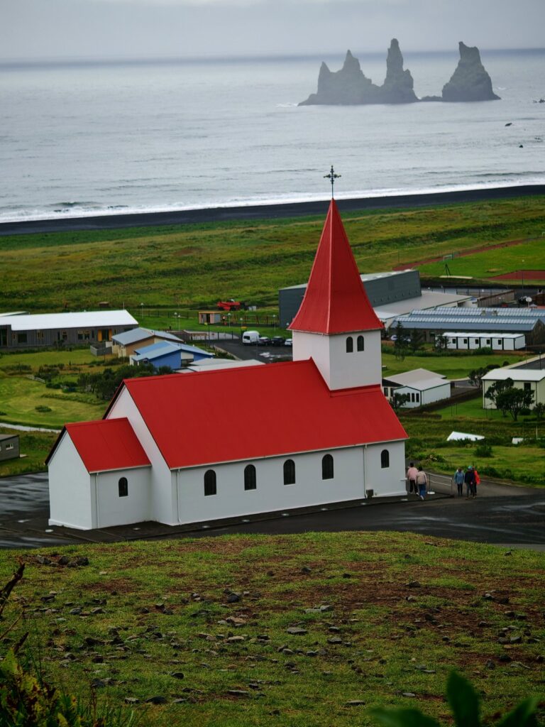 Chiesa bianca con tetto rosso e strada decorata con colori dell'arcobaleno
