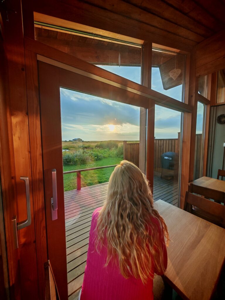 Interno di una stanza con vista sul tramonto, mentre una persona guarda fuori