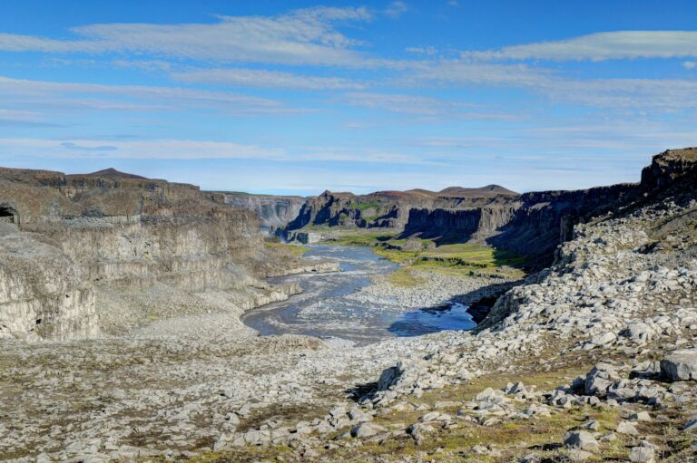 Gola ampia e paesaggio scavato, con acqua lontana e pareti rocciose
