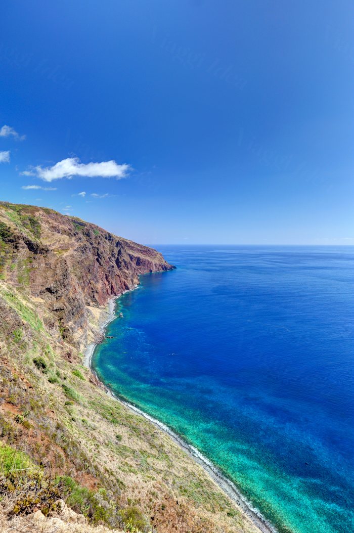 Costa alta e rocciosa che scende su un mare azzurro con fondali turchesi