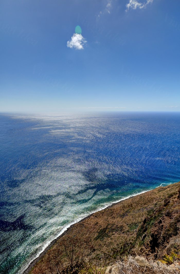 Vista dall'alto di un mare blu con onde bianche lungo una costa rocciosa