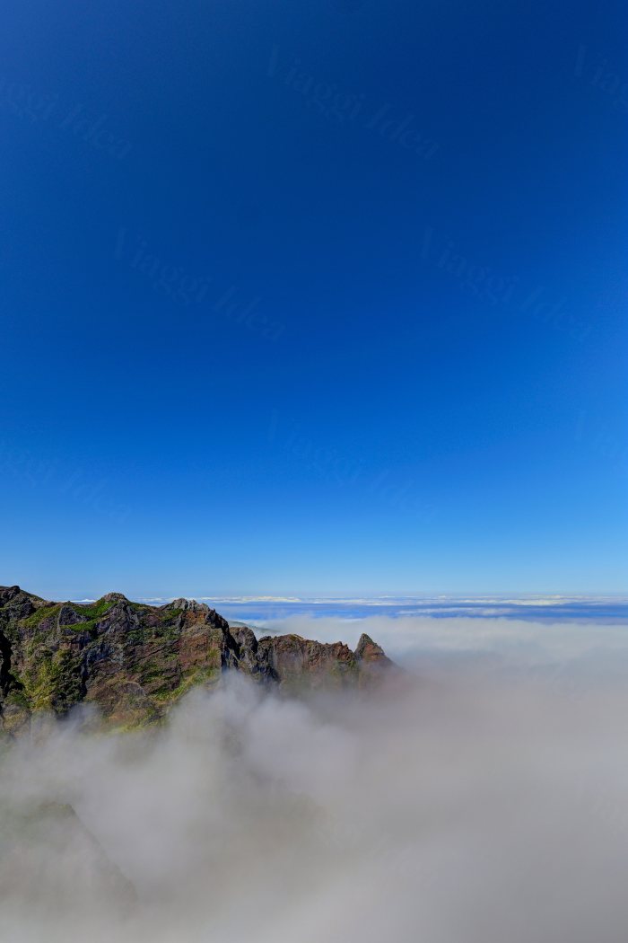 Vista di una montagna sopra le nuvole con cielo blu
