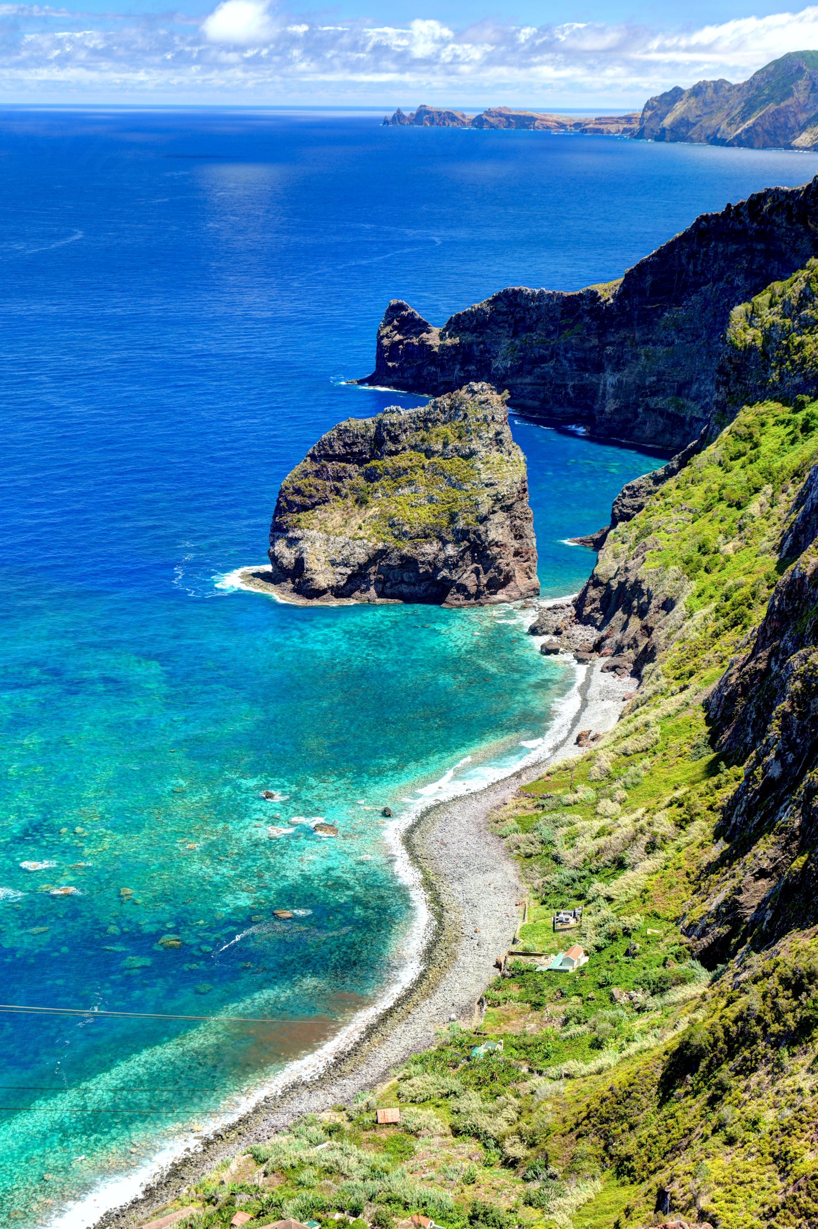 Vista dall'alto di una baia con mare turchese, scogli e costa verde