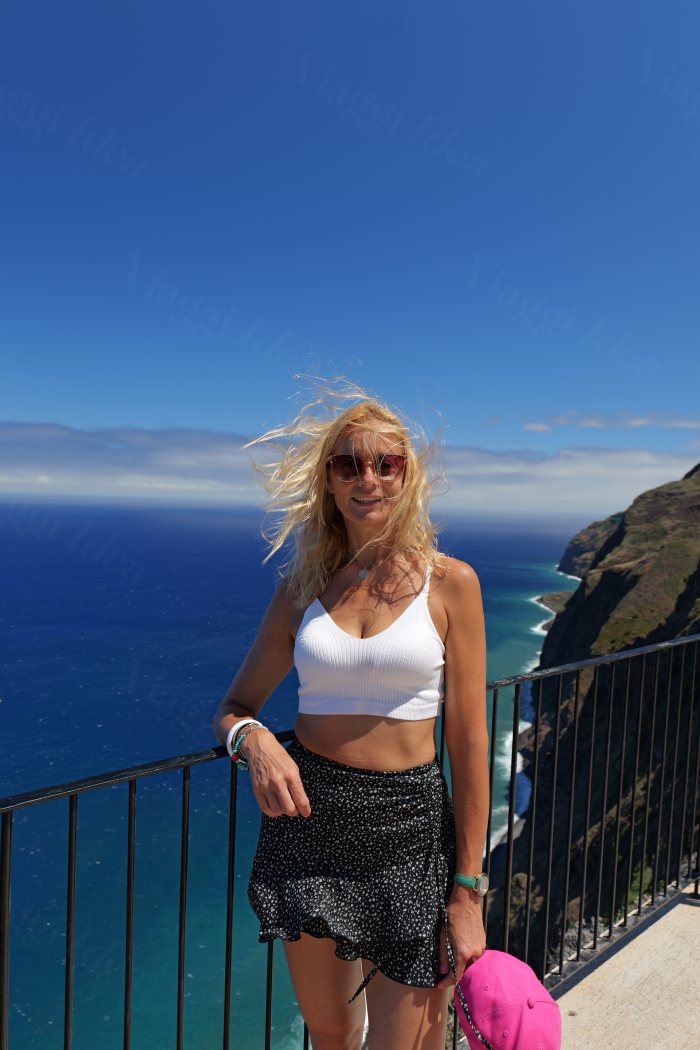 Donna appoggiata a un balcone panoramico con vista sul mare e sulle scogliere